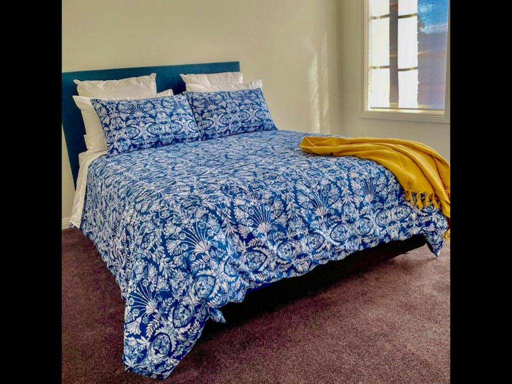 łóżko z niebiesko-białą kołdrą i poduszkami w obiekcie Ballarat CBD Accommodation 2 Bd Townhouse Talbot Terrace w mieście Ballarat