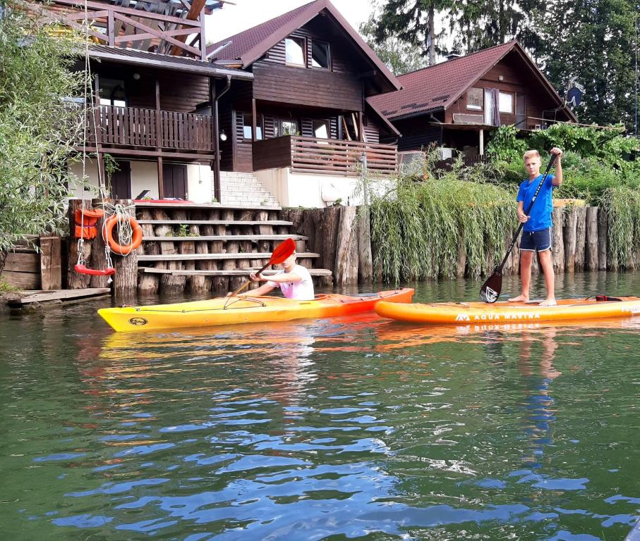 zwei Jungs in Kajaks auf dem Wasser vor einem Haus in der Unterkunft River Houses Ljubljanica in Ljubljana