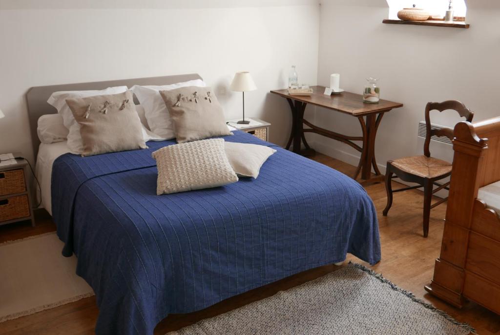 1 dormitorio con 1 cama azul, mesa y silla en Les Chambres du Moulin, en Susmiou