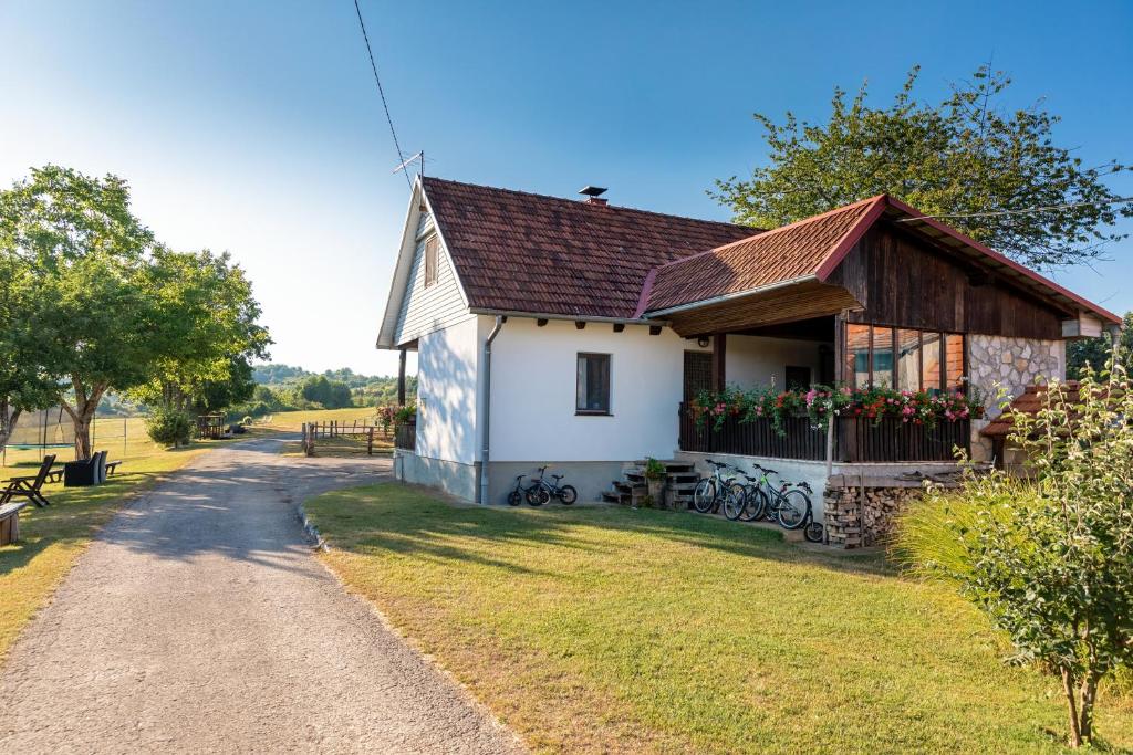 uma casa branca com um telhado castanho e uma estrada em Farmstay Kotić em Slunj