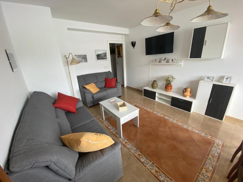 uma sala de estar com um sofá cinzento e almofadas vermelhas em Apartamento céntrico con vistas y cerca de playa em Puentedeume