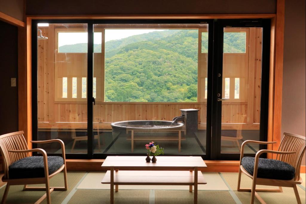 um quarto com uma grande janela com uma mesa e cadeiras em Yugawara Fuga em Yugawara