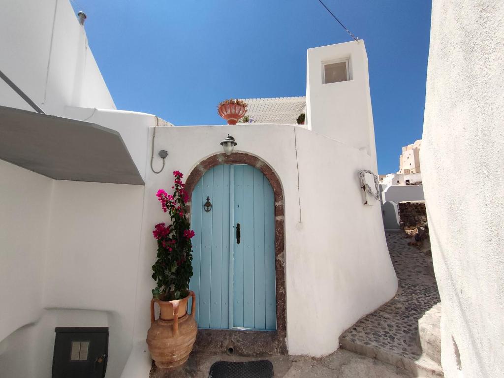 a blue door on a white building with flowers at Casanova's house in Emporio Santorini