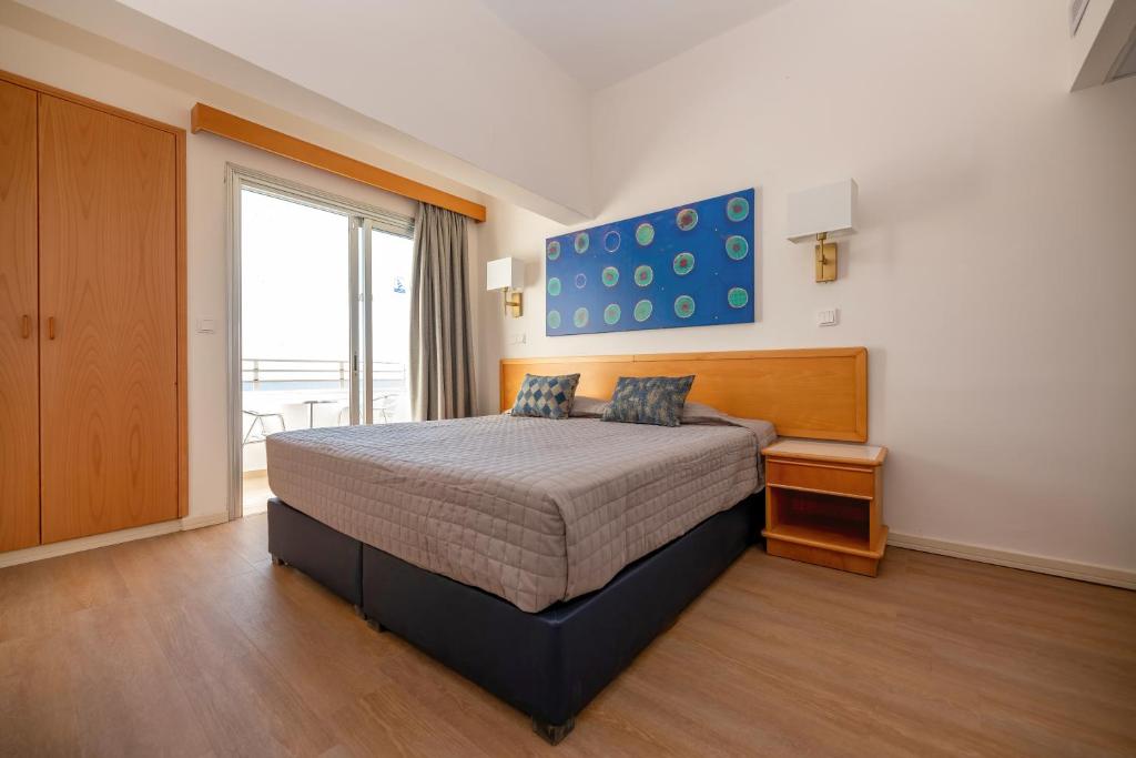 a bedroom with a bed and a large window at Tylos Beach Hotel in Kato Pyrgos