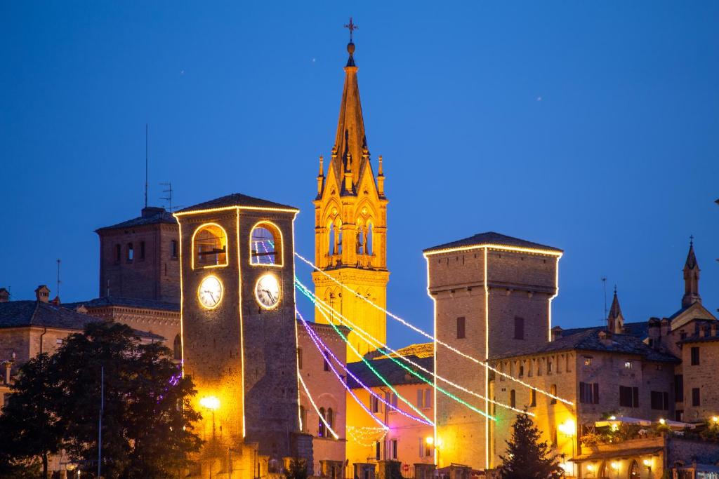 ein Gebäude mit einem Uhrturm vor einer Kirche in der Unterkunft casa vacanze asia in Castelvetro di Modena