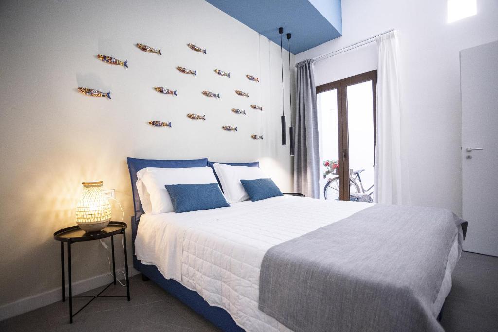 een slaapkamer met een groot bed met blauwe kussens bij Acquarò Suite Apartments in San Vito lo Capo