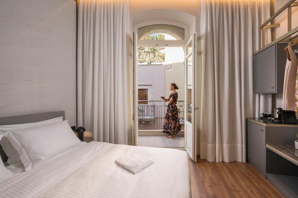 Eine Frau steht in einem Schlafzimmer mit einem Bett in der Unterkunft Veneri Boutique Suites in Chania