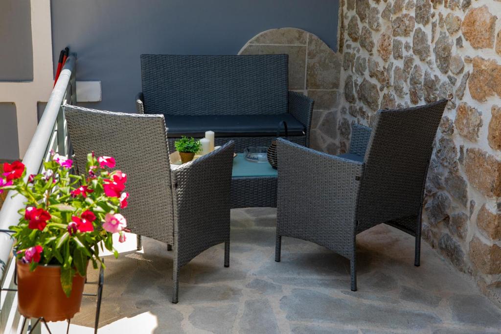 un patio con sillas de mimbre, una mesa y flores en ADRIAN'S LUXURY APARTMENTS 2 en Drepano