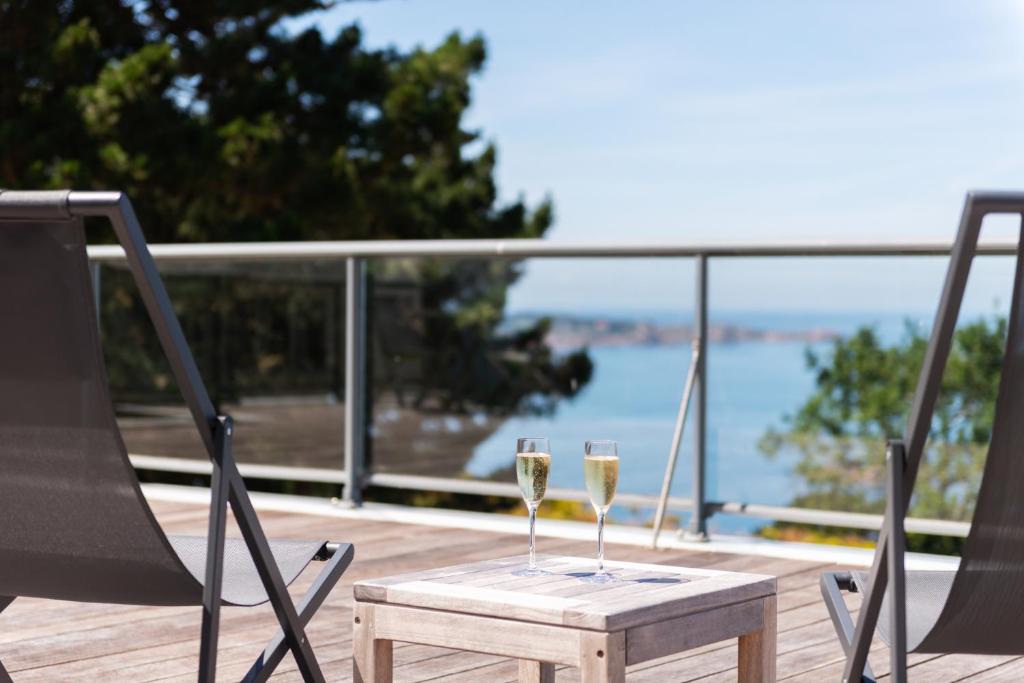 two glasses of wine on a table on a deck at Hôtel Les Costans, The Originals Relais in Perros-Guirec