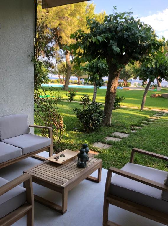a patio with a table and chairs and a park at Garden Oasis by the Sea - Pool & Parking in Agioi Theodoroi