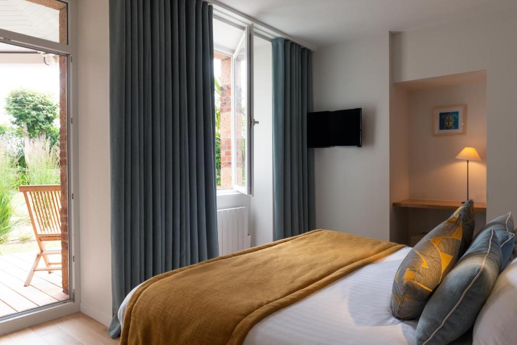 a bedroom with a bed and a large window at Hôtel Les Costans, The Originals Relais in Perros-Guirec