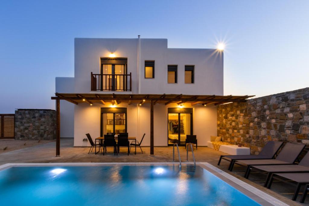 a villa with a swimming pool in front of a house at Cato Agro 1, Seafront Villa with Private Pool in Karpathos