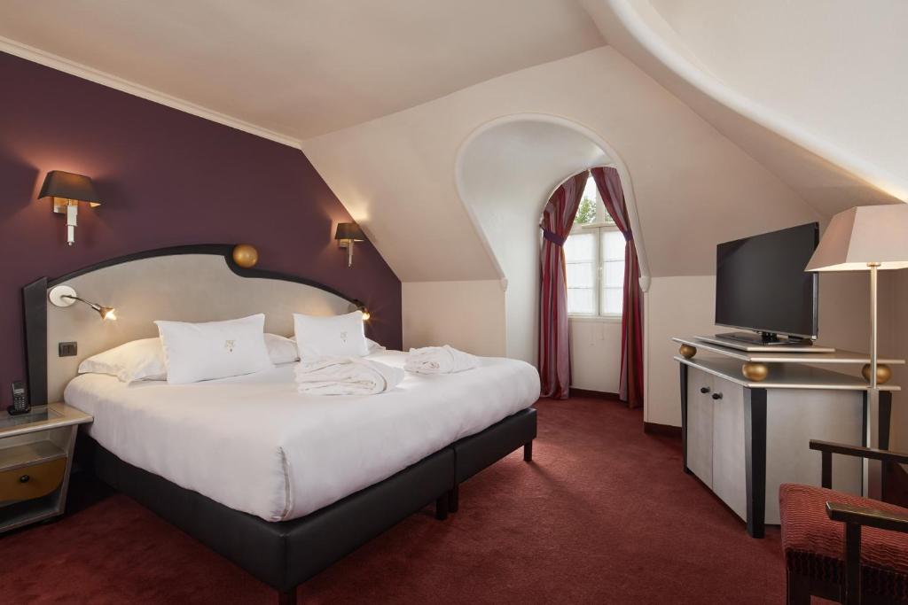 a bedroom with a large bed and a tv at Le Grand Hôtel Le Touquet-Paris-Plage in Le Touquet-Paris-Plage