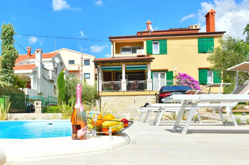 una bottiglia di vino e un cesto di frutta accanto a una casa di Villa Lux Nina with six bedrooms, private pool, sauna a Zara (Zadar)