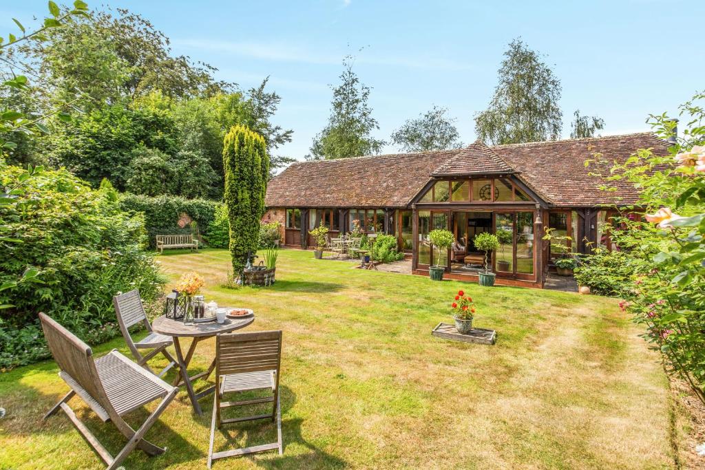 a garden with a house with a table and chairs at Carters Barn in Chipping Campden