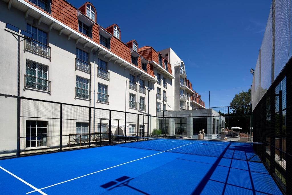 a tennis court in front of a building at Le Grand Hôtel Le Touquet-Paris-Plage in Le Touquet-Paris-Plage