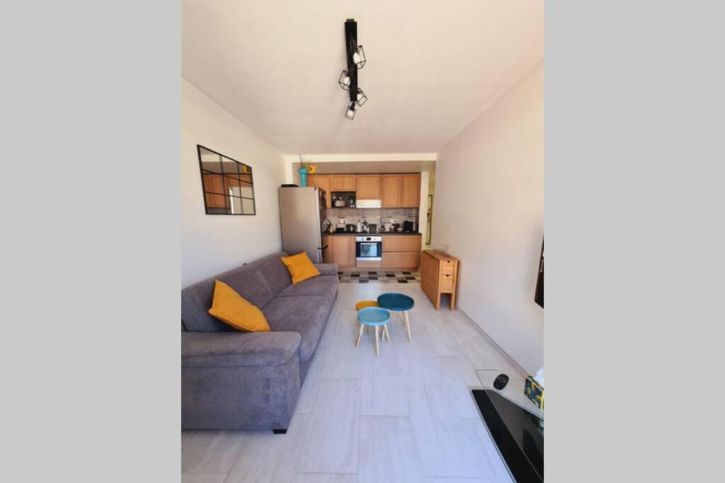 a living room with a couch and a kitchen at Saint Raphaël, bel appartement en centre ville ! in Saint-Raphaël