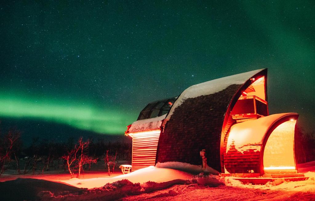 un igloo est éclairé sous les feux du nord dans l'établissement Tundrea Holiday Resort, à Kilpisjärvi