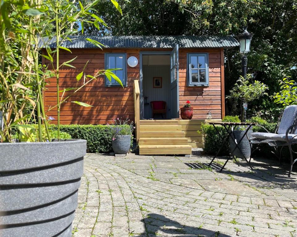 a small cabin with a porch and a patio at Holly Hut Shepherds Hut in Tower Bridge