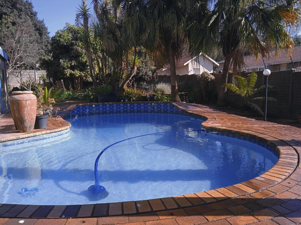 een zwembad met een waterslang in een tuin bij Lydiana Guesthouse in Pretoria