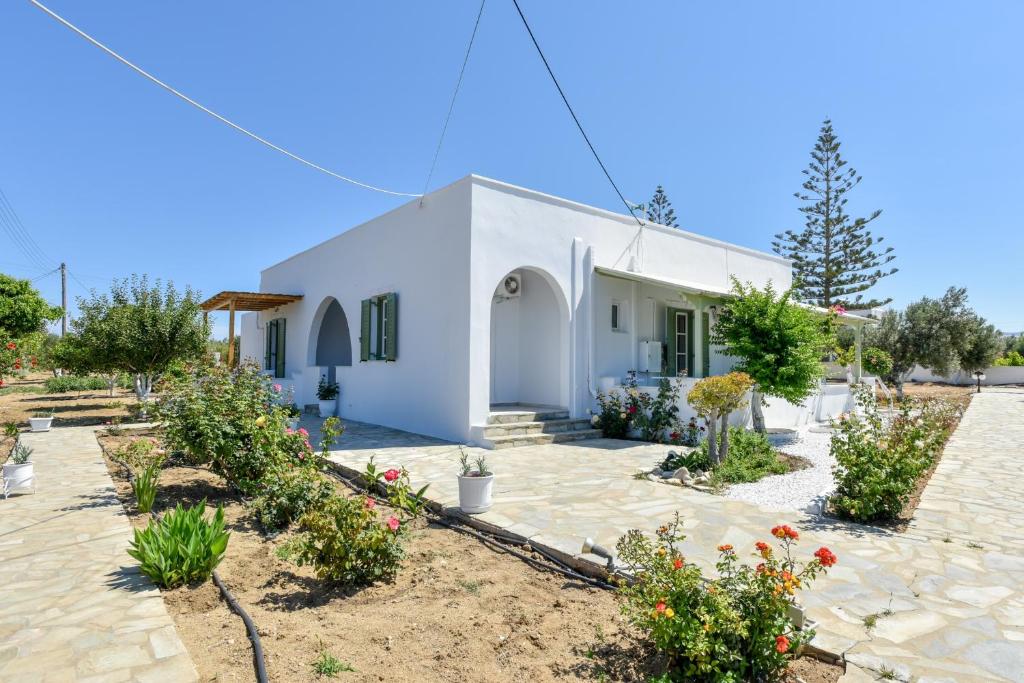 a white house with flowers in front of it at Naxian Garden of Senses in Agia Anna Naxos