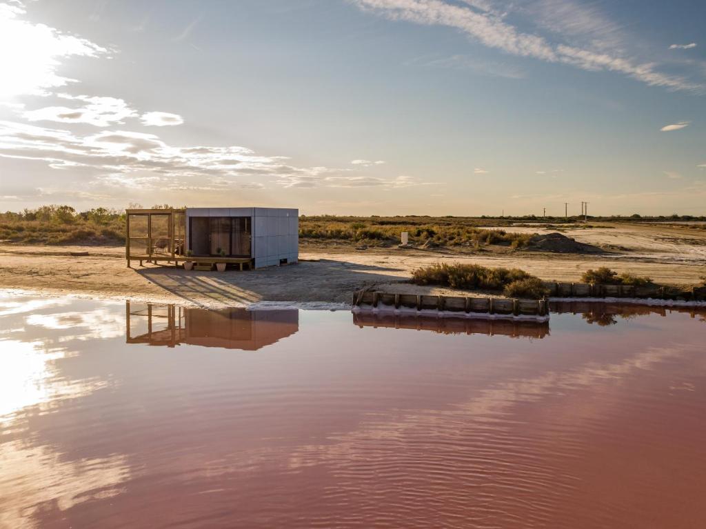 une maison sur la rive d'une masse d'eau dans l'établissement Cabane CASSIOPEE Aigues- Mortes, à Aigues-Mortes