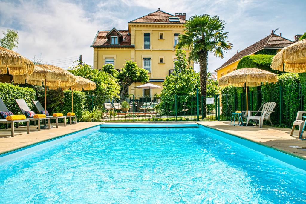 a swimming pool in front of a house at HOTEL DES DAUPHINS in Bourgoin