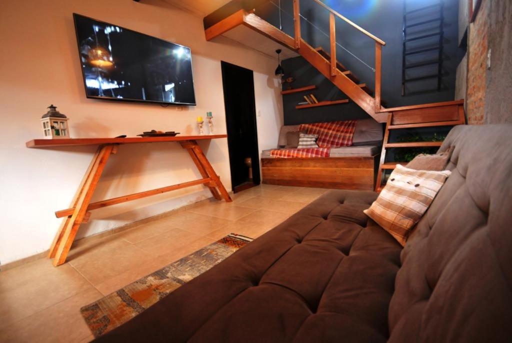 a living room with a couch and a tv and stairs at Pura vida in Chuy