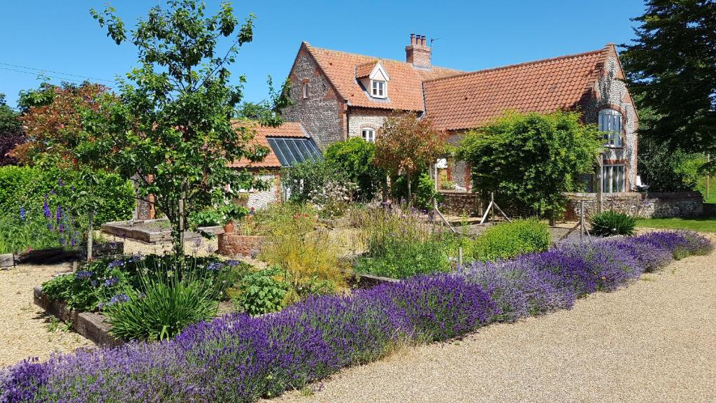 a garden with purple flowers in front of a house at Keepers Cottage Guest House in Holt
