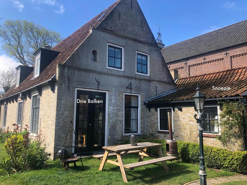 - un bâtiment avec une table de pique-nique devant dans l'établissement Herenweg Apartments, à Hollum