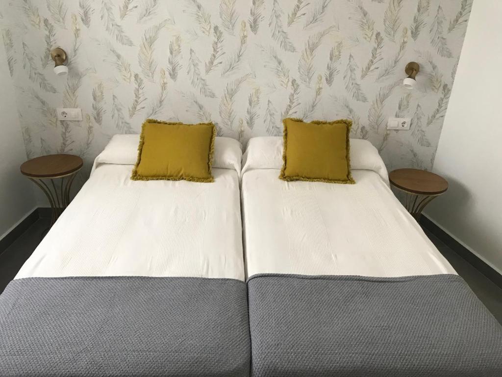 2 Betten in einem Zimmer mit 2 gelben Kissen in der Unterkunft Apartamentos Ad Theatrum in Merida