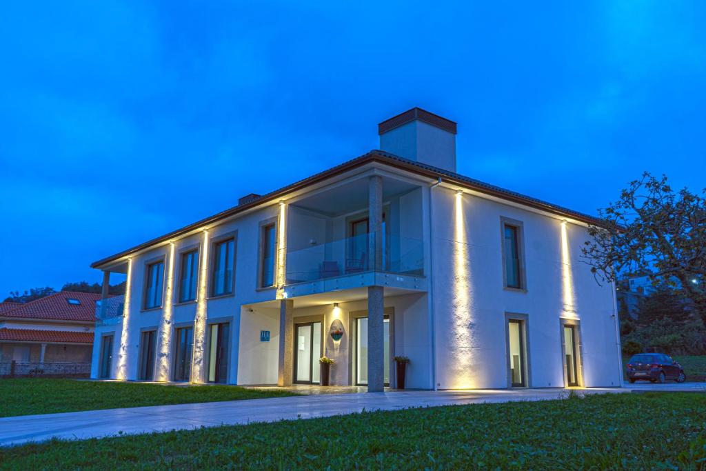 a large white building with lights on it at Aparthotel Ría de Lires in Lires