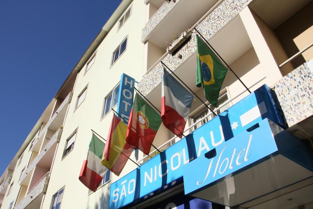 un hôtel arborant des drapeaux sur le côté d'un bâtiment dans l'établissement Hotel Sao Nicolau, à Braga