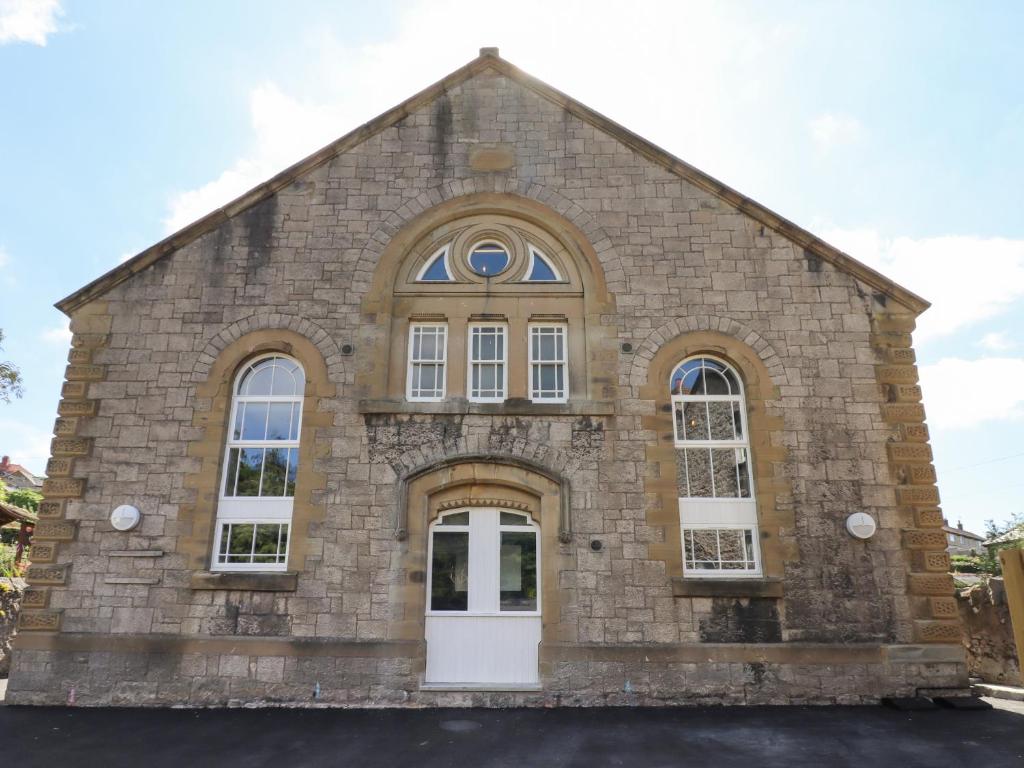 un antiguo edificio de piedra con una puerta blanca en The Poppy Fields Abode en Rhyl