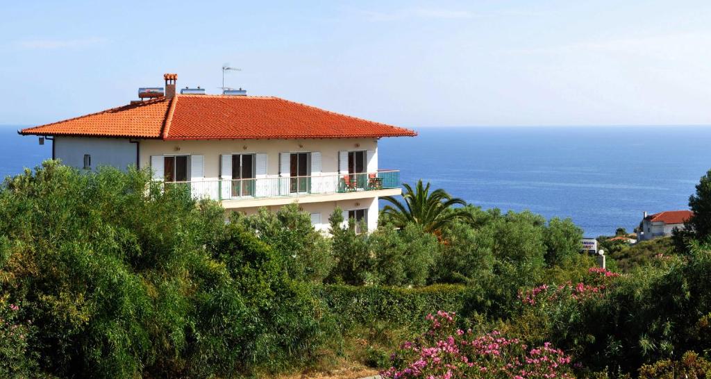 a house on a hill with the ocean in the background at Aris Pension in Agia Paraskevi