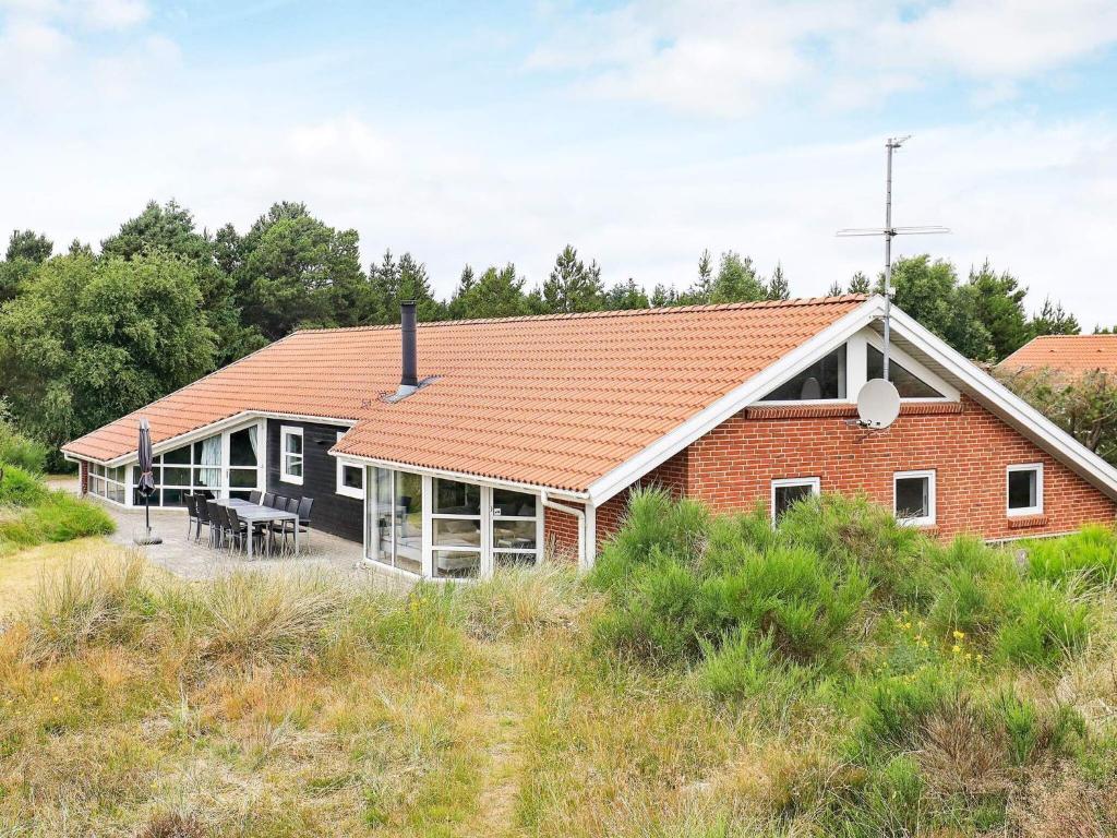 une maison en briques rouges avec un toit rouge dans l'établissement 12 person holiday home in Bl vand, à Blåvand