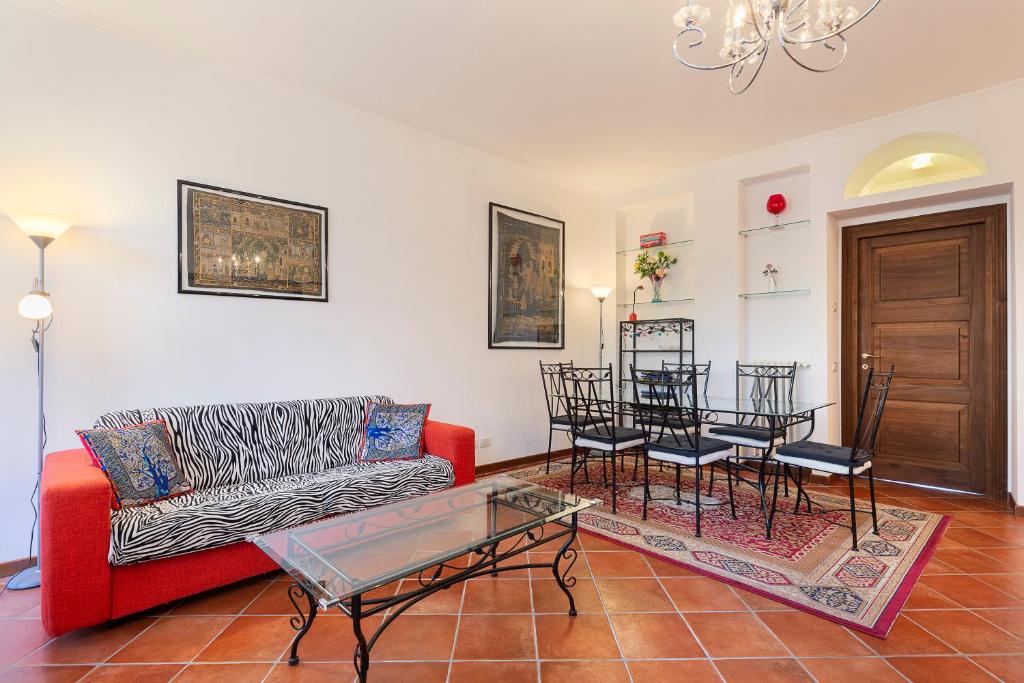salon z czerwoną kanapą i stołem w obiekcie Dolfin - Nel centro di Stresa - By Impero House w mieście Stresa