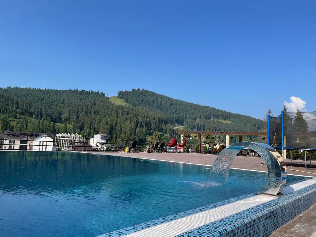 uma piscina com uma fonte de água em frente a uma montanha em Gold Palace em Bukovel
