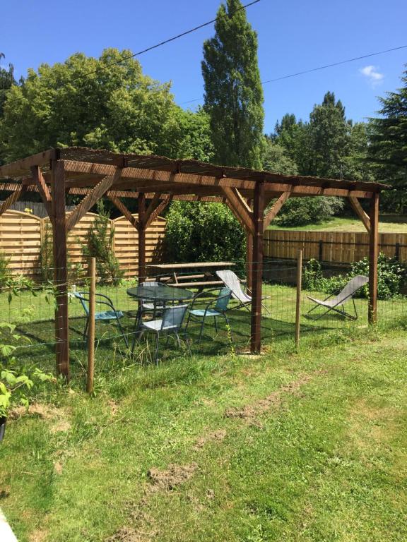 a wooden pergola with a table and chairs in the grass at Hippo-gite in Biron