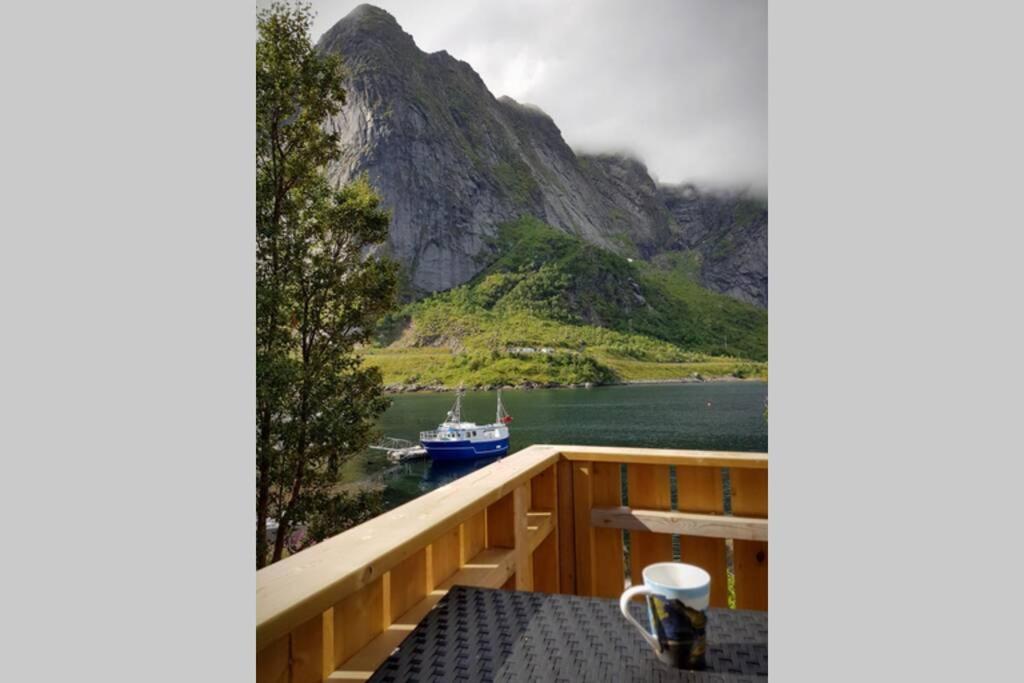 een balkon met uitzicht op een boot in het water bij Cozy House By The Fjord In The Heart Of Lofoten in Reine