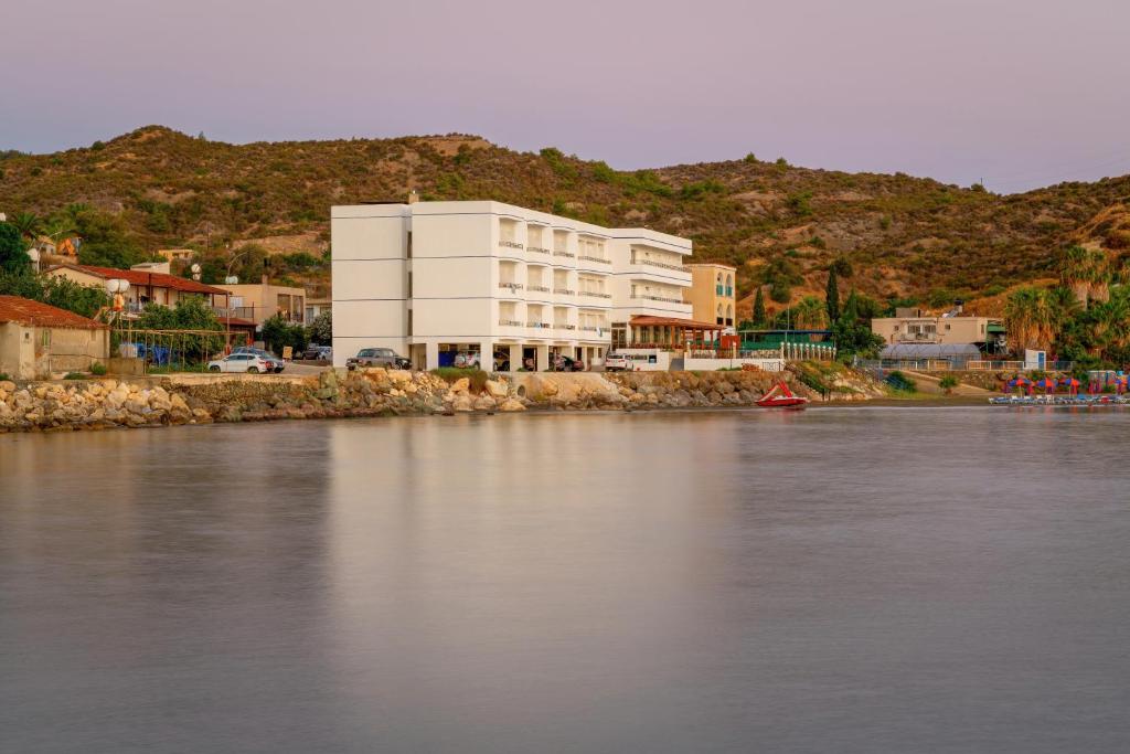 a large white building on the side of a river at Tylos Beach Hotel in Kato Pyrgos
