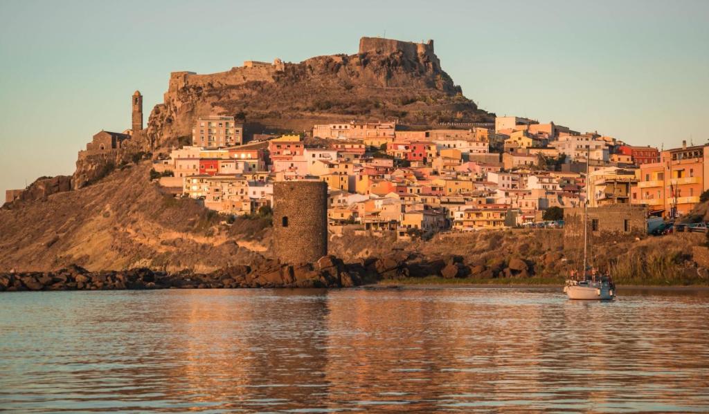 miasto na wzgórzu obok wody z łodzią w obiekcie La terra del benessere w mieście Castelsardo