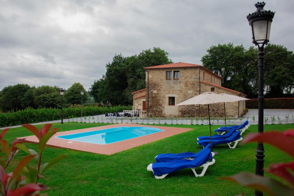 dwa krzesła i parasol obok basenu w obiekcie Casa Rural Camino Real w mieście Melide