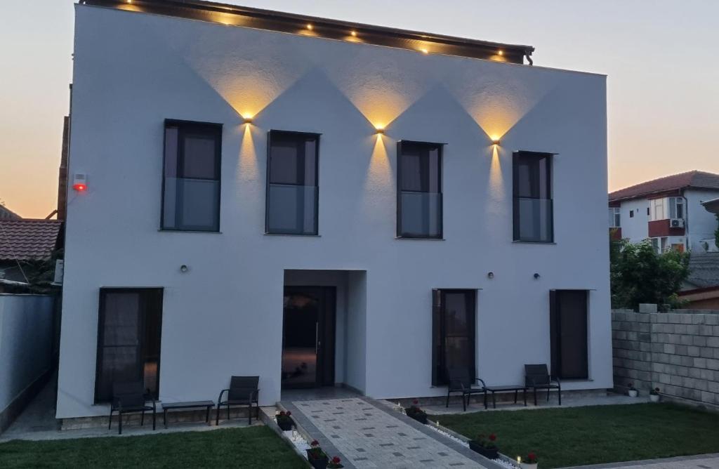 a white house with black windows and lights at CHG BOUTIQUE HOTEL in Costinesti