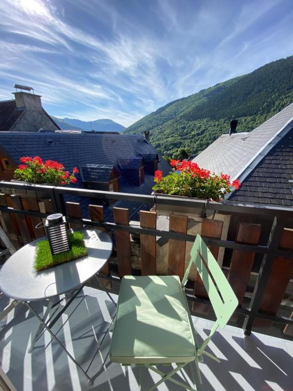 a balcony with a table and chairs and flowers at La Maisouneta in Cazeaux-de-Larboust