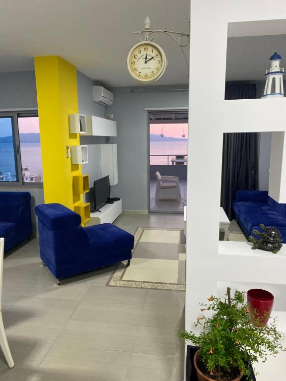 sala de estar con sillas azules y reloj en Jasmine Apartments, en Sarandë