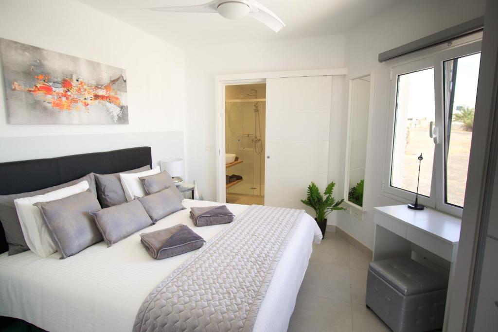 - une chambre blanche avec un grand lit blanc et des oreillers dans l'établissement Apartment El Sueño - GREAT SEA VIEWS - infinity POOL - free Wifi- smart TV-Residence Senator, à Costa Teguise