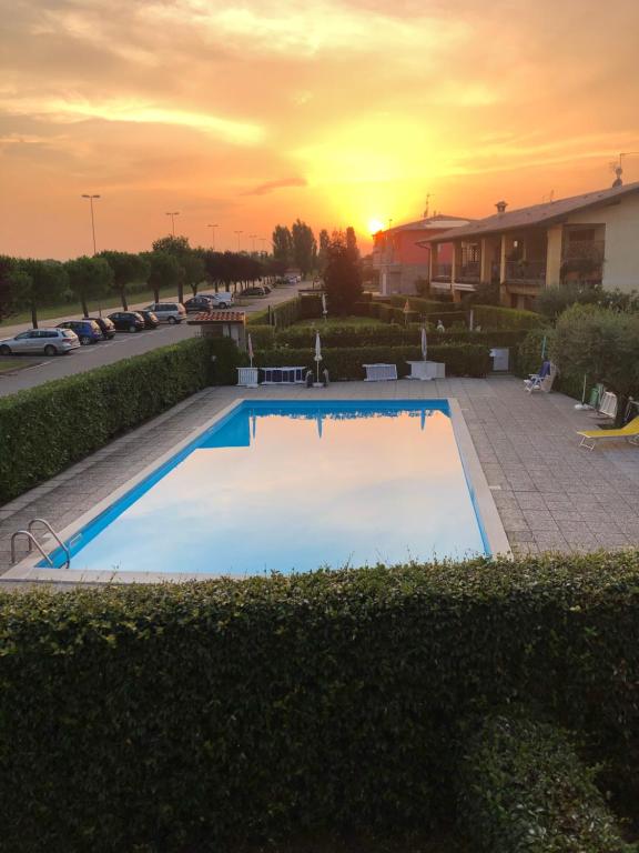 une piscine vide avec vue sur le coucher du soleil en arrière-plan dans l'établissement Sirmione Emma Appartamento, à Sirmione