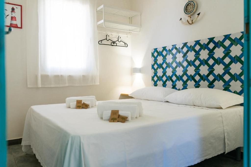 - une chambre avec un grand lit blanc et une tête de lit bleue dans l'établissement Albarìa Favignana Apartments, à Favignana