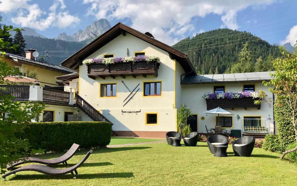 ein Haus mit Stühlen in einem Hof mit Bergen in der Unterkunft Haus Thomas in Werfenweng